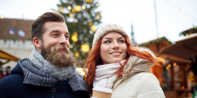 holidays, winter, christmas, hot drinks and people concept - happy couple of tourists in warm clothes drinking coffee from disposable paper cups in old town