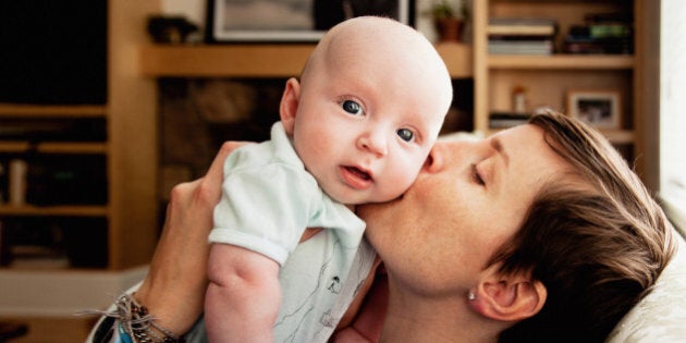 Infant boy being kissed by mother