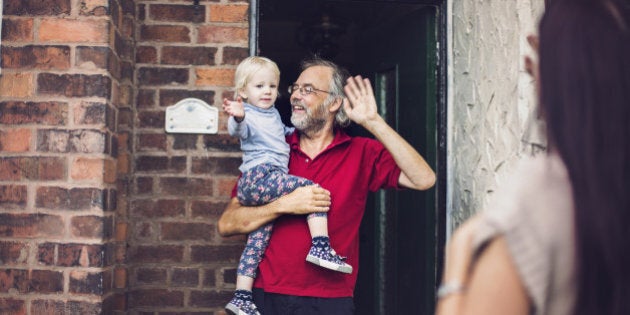 Happy smiling little toddler girl with her Grandpa waving goodbye to her Mummy who is leaving to go to work