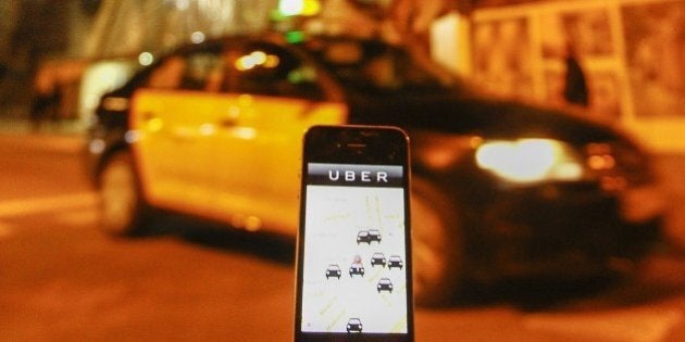 The Uber app is seen on a smartphone past a cab waiting for clients near the Sagrada Familia in Barcelona, on December 9, 2014. A judge on December 9, 2014 banned the popular smartphone taxi service Uber from operating in Spain, court officials said, following similar prohibition action in several other countries. AFP PHOTO/ QUIQUE GARCIA (Photo credit should read QUIQUE GARCIA/AFP/Getty Images)