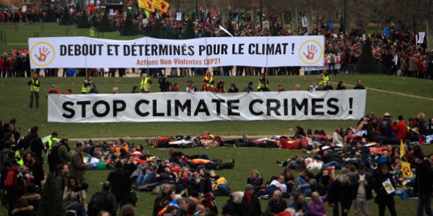 Activists gather during a demonstration near the Eiffel Tower, in Paris, Saturday, Dec.12, 2015 during the COP21, the United Nations Climate Change Conference. As organizers of the Paris climate talks presented what they hope is a final draft of the accord, protesters from environmental and human rights groups gather to call attention to populations threatened by rising seas and increasing droughts and floods. Banner behind reads: Standing and decided for climate. (AP Photo/Thibault Camus)