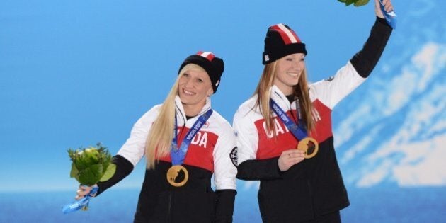 A picture taken with a robotic camera shows (from L) shows Canada's gold medalists pilot Kaillie Humphries and brakewoman Heather Moyse celebrating during the Women's Bobsleigh Medal Ceremony at the Sochi medals plaza during the Sochi Winter Olympics on February 20, 2014. AFP PHOTO / ANTONIN THUILLIER (Photo credit should read ANTONIN THUILLIER/AFP/Getty Images)