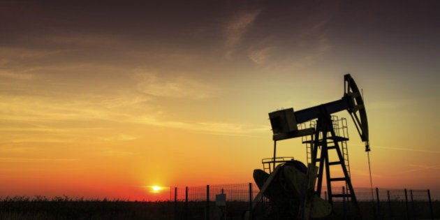 Operating oil and gas well profiled on sunset sky