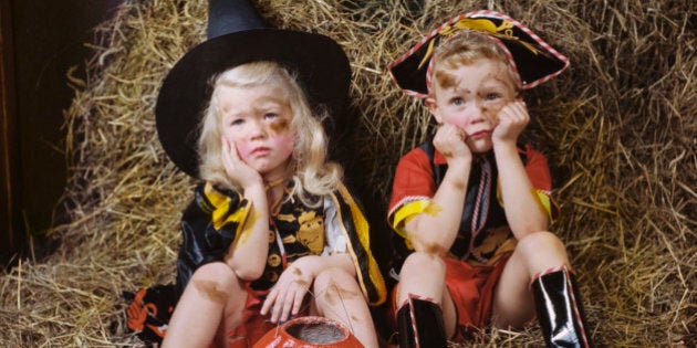 Children wearing costumes sitting on hay with sad faces