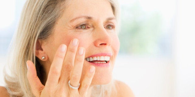 USA, New Jersey, Jersey City, Portrait of senior woman applying moisturizer