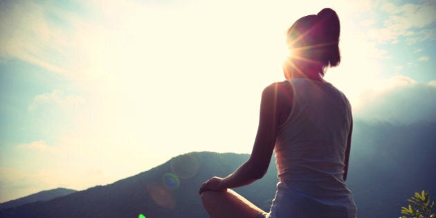 young yoga woman at sunrise mountain peak