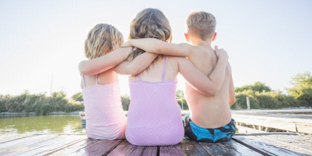 Caucasian children sitting on dock