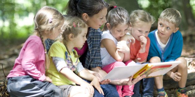 Kindergarten teacher reading with kids in a wood kindergarten
