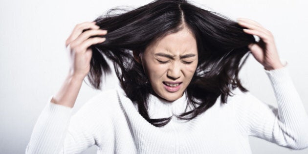 A furious Chinese woman tearing her hair out, studio shot.