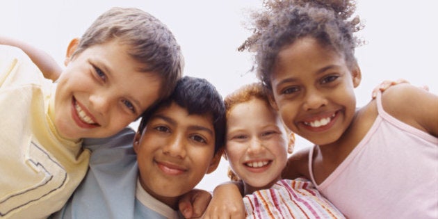 Low angle view of two boys and two girls (6-8) standing in a huddle