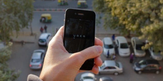 The Uber smartphone app, used to book taxis using its service, is pictured over a parking lot as auto-rickshaws (background) ply a road in the Indian capital New Delhi on December 7, 2014. An Uber taxi driver allegedly raped a 25-year-old passenger in the Indian capital before threatening to kill her, police said December 7, in a blow to the company's safety-conscious image. AFP PHOTO/TENGKU BAHAR (Photo credit should read TENGKU BAHAR/AFP/Getty Images)