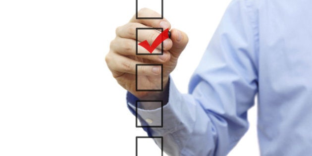 Young businessman checking mark on checklist with marker. Isolated on white.