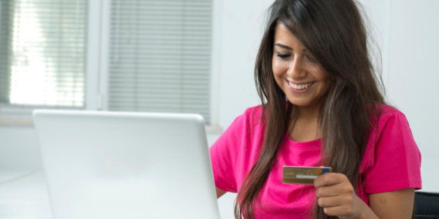 Smiling young woman shopping online with credit card and laptop computer