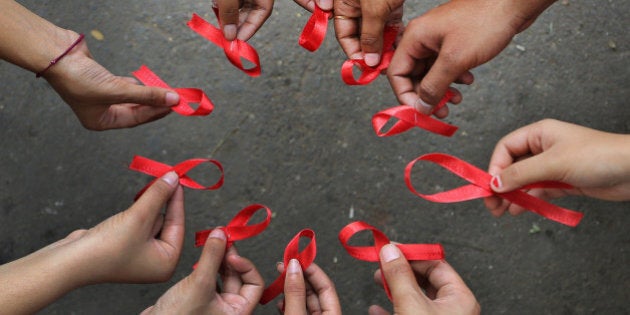 Activists of a non-governmental organization display red ribbons, symbol of HIV-AIDS awareness, as they pose for photographers during an awareness campaign on World AIDS Day, in a business district of Bangalore, India, Sunday, Dec. 1, 2013. UNAIDS lists India as third worst Human Immunodeficiency Virus (HIV) affected country with about 2.5 million infected people after South Africa with 6 million and Nigeria with 2.9 million. (AP Photo/Aijaz Rahi)