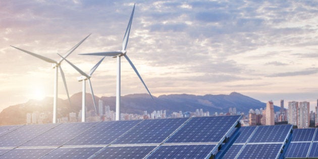 solar panels and wind turbines under sky and clouds with city on horizon. Sunrise