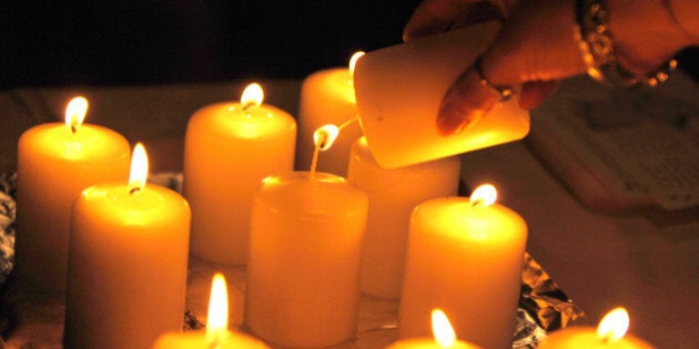 Hayder Kadhim-- 12/06/2006 -A woman lights a candle during a ceremony in Toronto marking the 17th anniversary of the Ecole Polytechnique massacre in Montreal that left 14 women dead. (Photo by Carlos Osorio/Toronto Star via Getty Images)