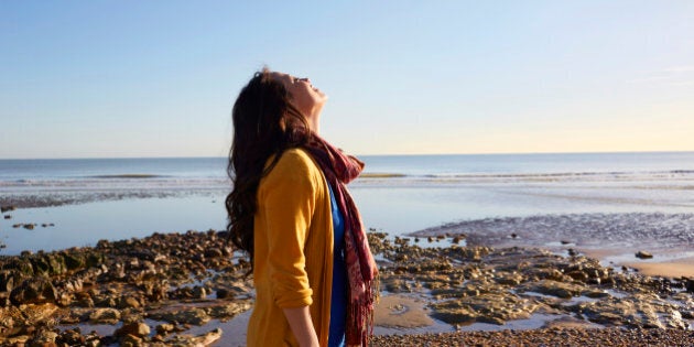 Woman on the beach breathing in the fresh air