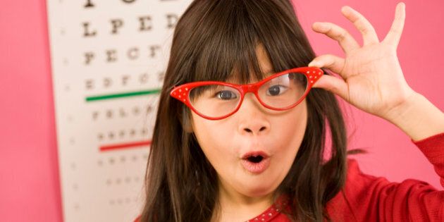 Girl wearing eyeglasses in front of eye chart