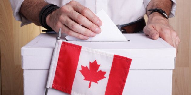 A man casting his vote. The Canadian flag is in front of the ballot box