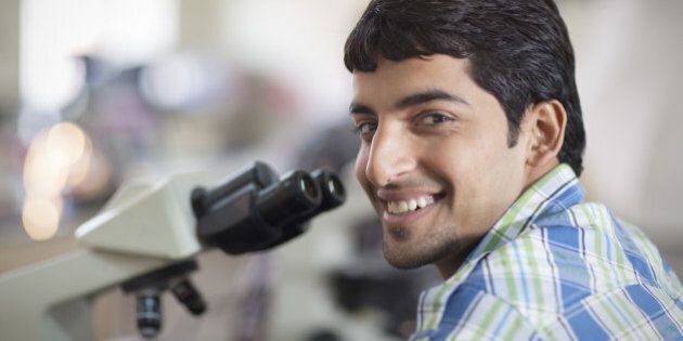 Smiling Indian Student With Microscope In A Laboratory
