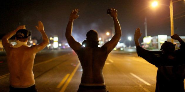 FERGUSON, MO - AUGUST 17: Demonstrators raise their arms and chant, 'Hands up, Don't Shoot', as police clear them from the street as they protest the shooting death of Michael Brown on August 17, 2014 in Ferguson, Missouri. Police sprayed pepper spray, shot smoke, gas and flash grenades as violent outbreaks have taken place in Ferguson since the shooting death of Michael Brown by a Ferguson police officer on August 9th. (Photo by Joe Raedle/Getty Images)