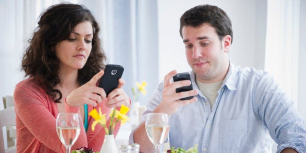 USA, New Jersey, Jersey City, Couple having dinner and text messaging