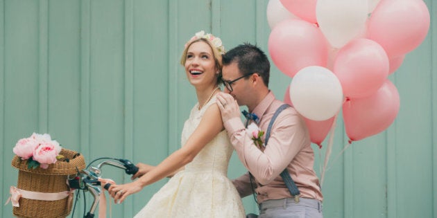 Happy couple smiling on a wedding day, with retro bike and vintage outfit.