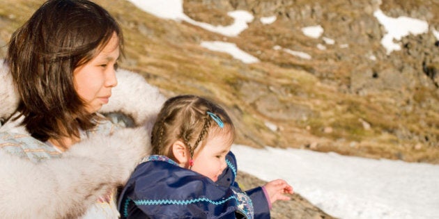 An Inuit mother and her daughter on the remote tundra of Baffin Island wearing traditional dress in late spring. Click to see similar images of this model.