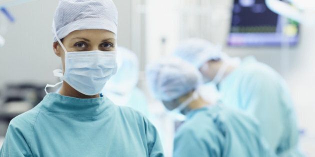 Portrait of confident female surgeon with colleagues working in operating room