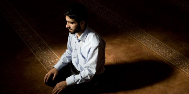 Young muslim man praying in mosque