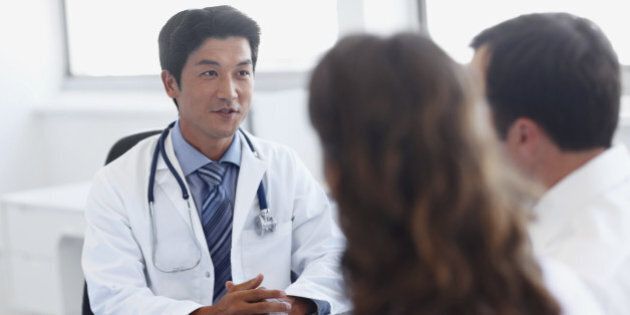 A handsome asian doctor talking with clients in his office