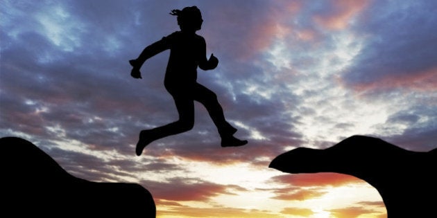 Woman jump over canyon at a sunset