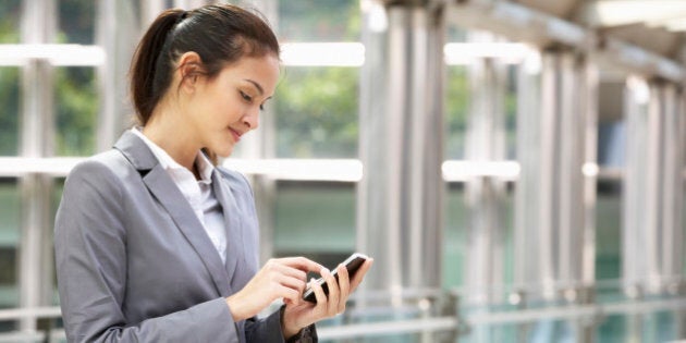 Hispanic Businesswoman Outside Office On Mobile Phone