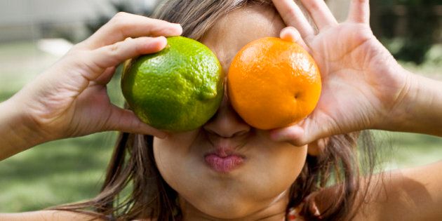 Young girl making silly face with fruit.