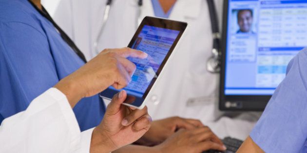 Doctors using digital tablet together in hospital