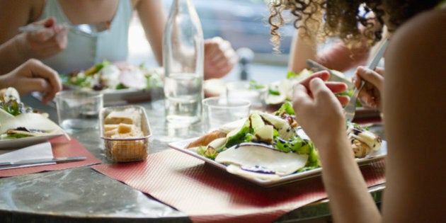 Friends enjoying meal in cafe, cropped