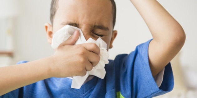 Mixed race boy blowing his nose