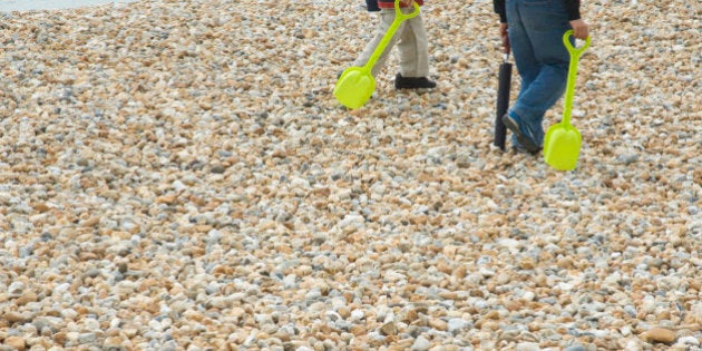 Children carrying bright yellow spades on beach