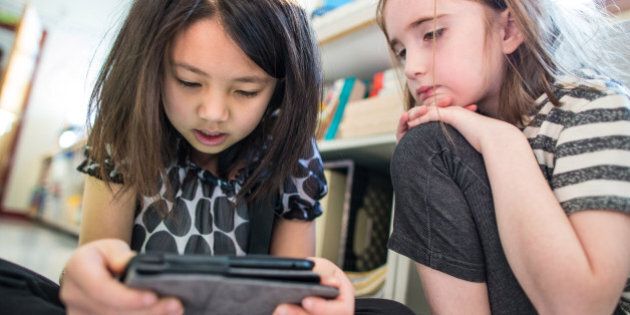MILTON, MA - MARCH 4: Students Caylie Zhong, 7, left, and Lillian McLaughlin, 7, use a Kindle to read a story in a second grade English class at Cunningham Elementary School in Milton. The Milton School District is in the midst of installing the infrastructure needed for full wireless coverage in all six schools by this fall. (Photo by Aram Boghosian for The Boston Globe via Getty Images)