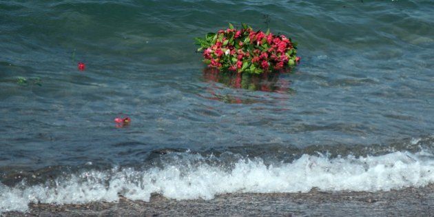 MUGLA, TURKEY - SEPTEMBER 4: Flowers are seen in the sea as people commemorate Aylan Kurdi, the three-year-old boy dressed in shorts and a red T-shirt, and 12 Syrians who drowned in the Aegean Sea after two boats filled with refugees en route to Greece sank, at the beach where they washed ashore in Mugla, Turkey on September 4, 2015. (Photo by Mustafa Ciftci/Anadolu Agency/Getty Images)