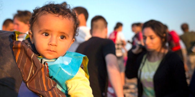 A migrant baby looks towards the see as migrants arrive on a dinghy at the southeastern island of Kos, Greece, after crossing from Turkey, Thursday, Aug. 13, 2015. Greece has become the main gateway to Europe for tens of thousands of refugees and economic migrants, mainly Syrians fleeing war, as fighting in Libya has made the alternative route from north Africa to Italy increasingly dangerous. (AP Photo/Alexander Zemlianichenko)