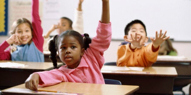 School children raising their hands in class