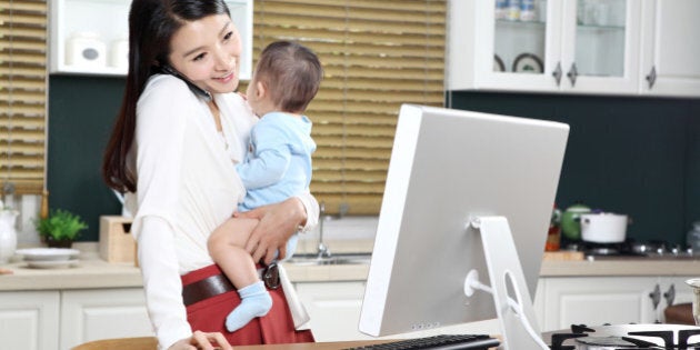 Businesswoman using computer while carrying baby