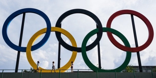 Youngsters walk past the Olympic rings at Madureira Park, the third largest park in Rio de Janeiro, Brazil, on July 1, 2015, 400 days ahead of the Rio 2016 Olympic games. The 12-meter-high symbol was shipped from Great Britain after having decorated the Tyne Bridge in Newcastle during the 2012 London Olympic Games. AFP PHOTO / YASUYOSHI CHIBA (Photo credit should read YASUYOSHI CHIBA/AFP/Getty Images)