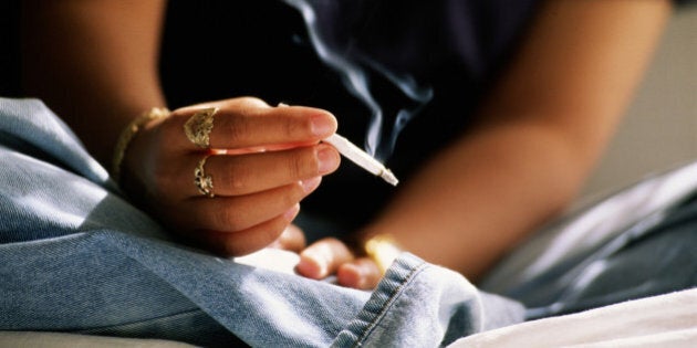 Teenager (16-18) smoking hand rolled cigarette