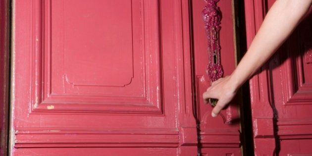 Woman closing pink door of apartment