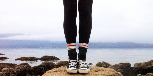 Teenage girl standing along the shoreline.