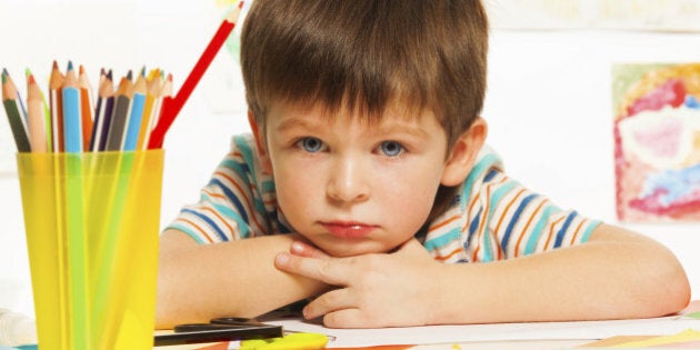 Close portrait of boy with pencils and color paper