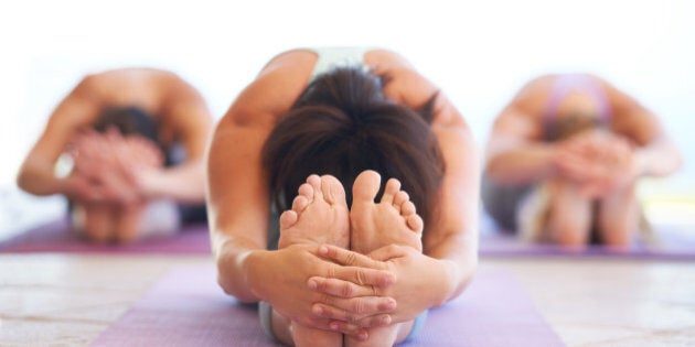 Young yoga instructor leading a class in stretching