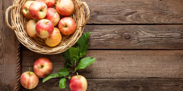 fresh apples in wicker basket on wooden table